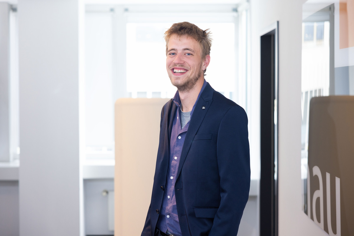 Porträtfoto eines Mannes, der in einem Büroflur steht.