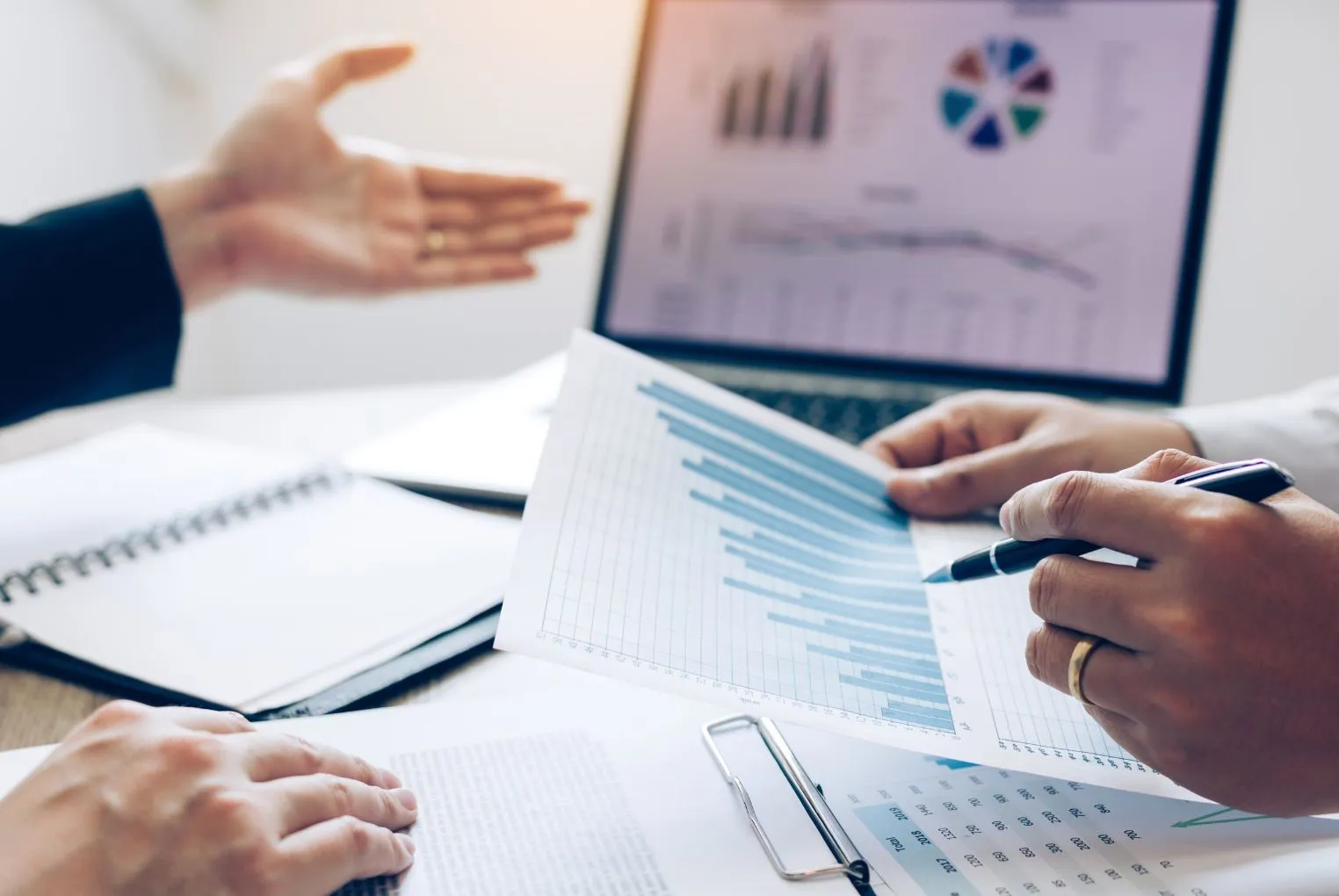 Bild: Zwei Personen sitzen gegenüber, eine Person zeigt auf Bildschirm