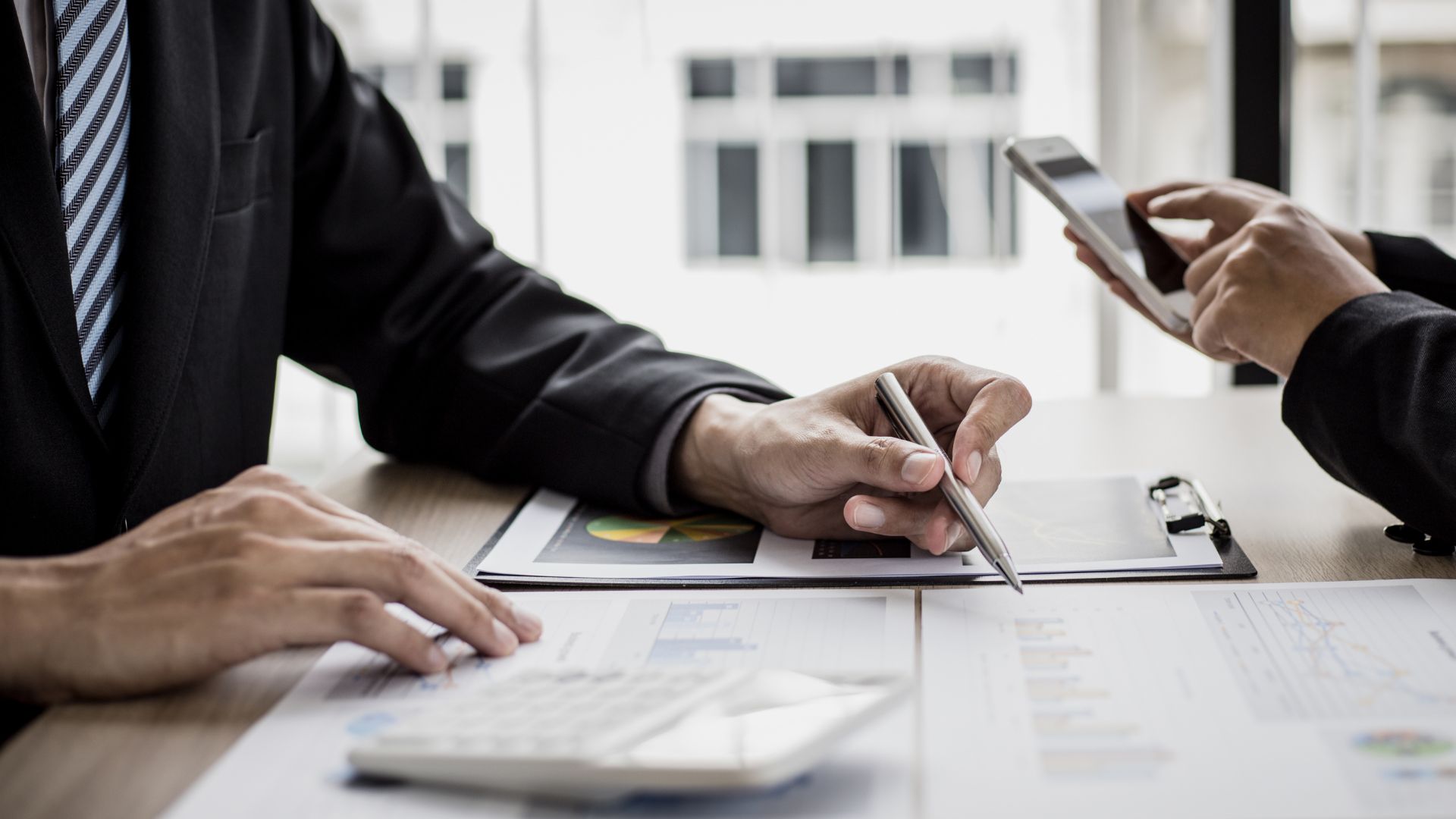 Bild: zwei Personen sitzen sich gegenüber, eine Person schreibt, die andere Person ist am Tablet